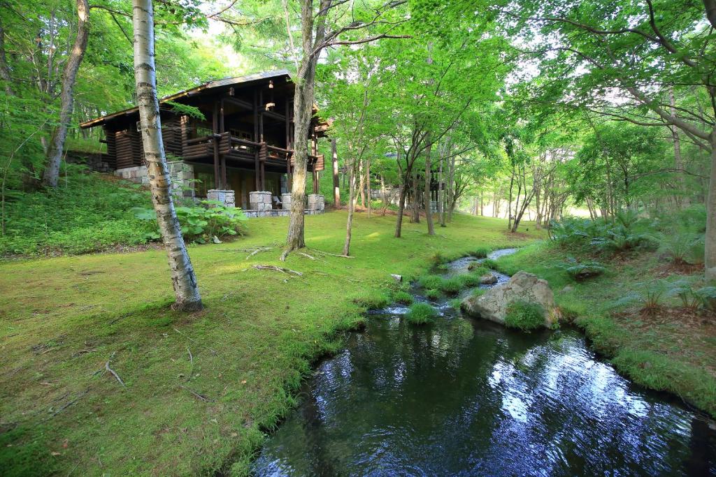 une rivière dans une forêt avec un bâtiment à côté dans l'établissement Hotel Nidom, à Tomakomai