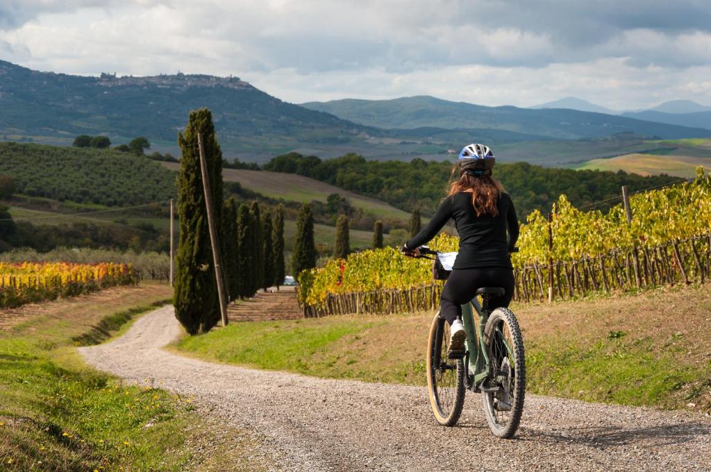 une femme faisant du vélo sur un chemin de gravier dans l'établissement Podere Lorena, à Monteriggioni