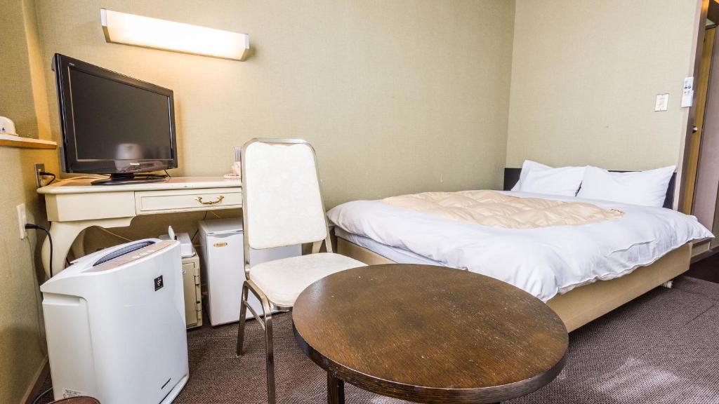 une chambre avec un lit, une table et une télévision dans l'établissement Ooedo Onsen Monogatari Nagayama, à Kaga