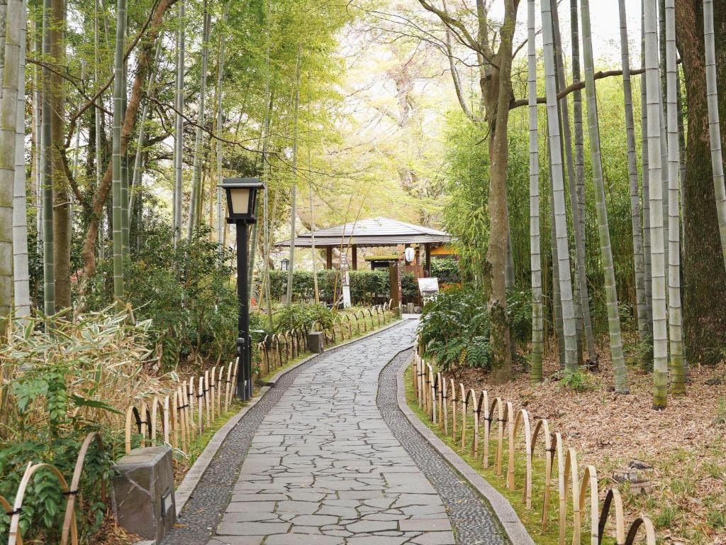 un chemin de pierre dans une forêt de bambous avec un belvédère dans l'établissement Shuzenji Onsen Hotel Takitei, à Izu
