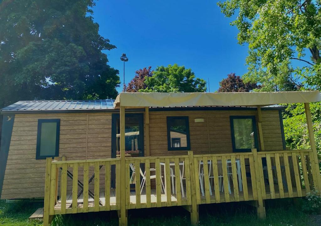 une petite maison avec une terrasse couverte et un toit dans l'établissement Camping Bois et Toilés, à Peyraud