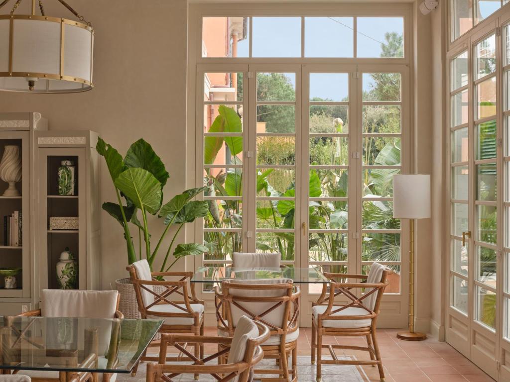 - une salle à manger avec une table, des chaises et de grandes fenêtres dans l'établissement Pensione America - Adults only, à Forte dei Marmi