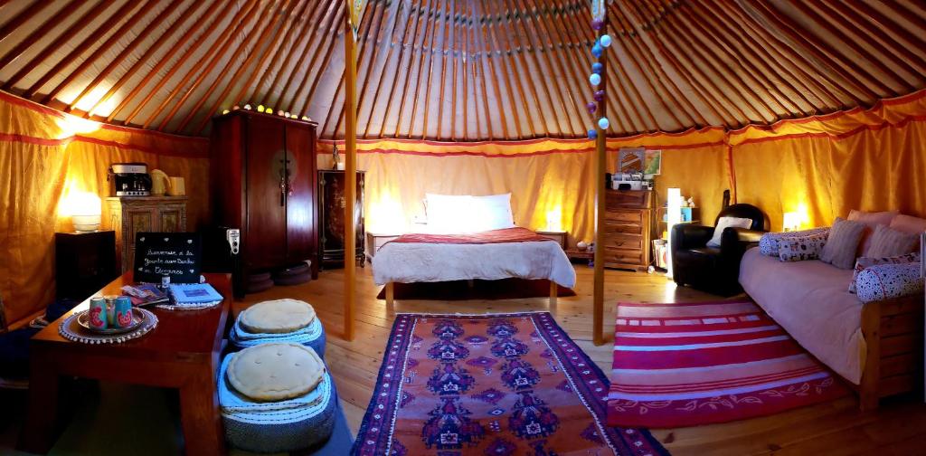 - une chambre dans une yourte avec un lit et un canapé dans l'établissement La Yourte aux Bambous en Cévennes, à Saint-André-de-Majencoules