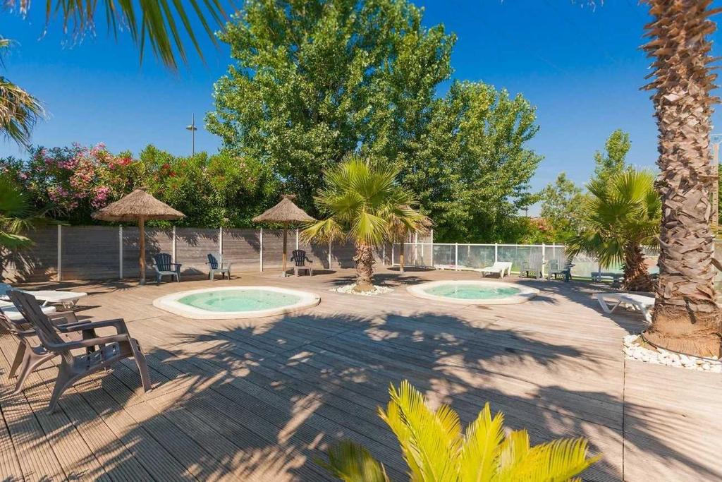 un patio avec 2 piscines et des palmiers dans l'établissement Camping 4 étoiles - Parc aquatique - eeiagh, à Sérignan