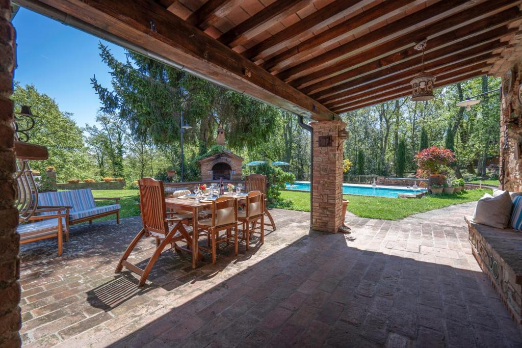 un patio avec une table et des chaises sous une pergola en bois dans l'établissement Grace Home, Pool, Wifi, Gambassi Terme, à Gambassi Terme