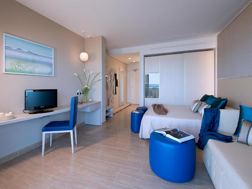 une chambre avec un lit, un canapé et une télévision dans l'établissement Hotel I Ginepri, à Marina di Castagneto Carducci