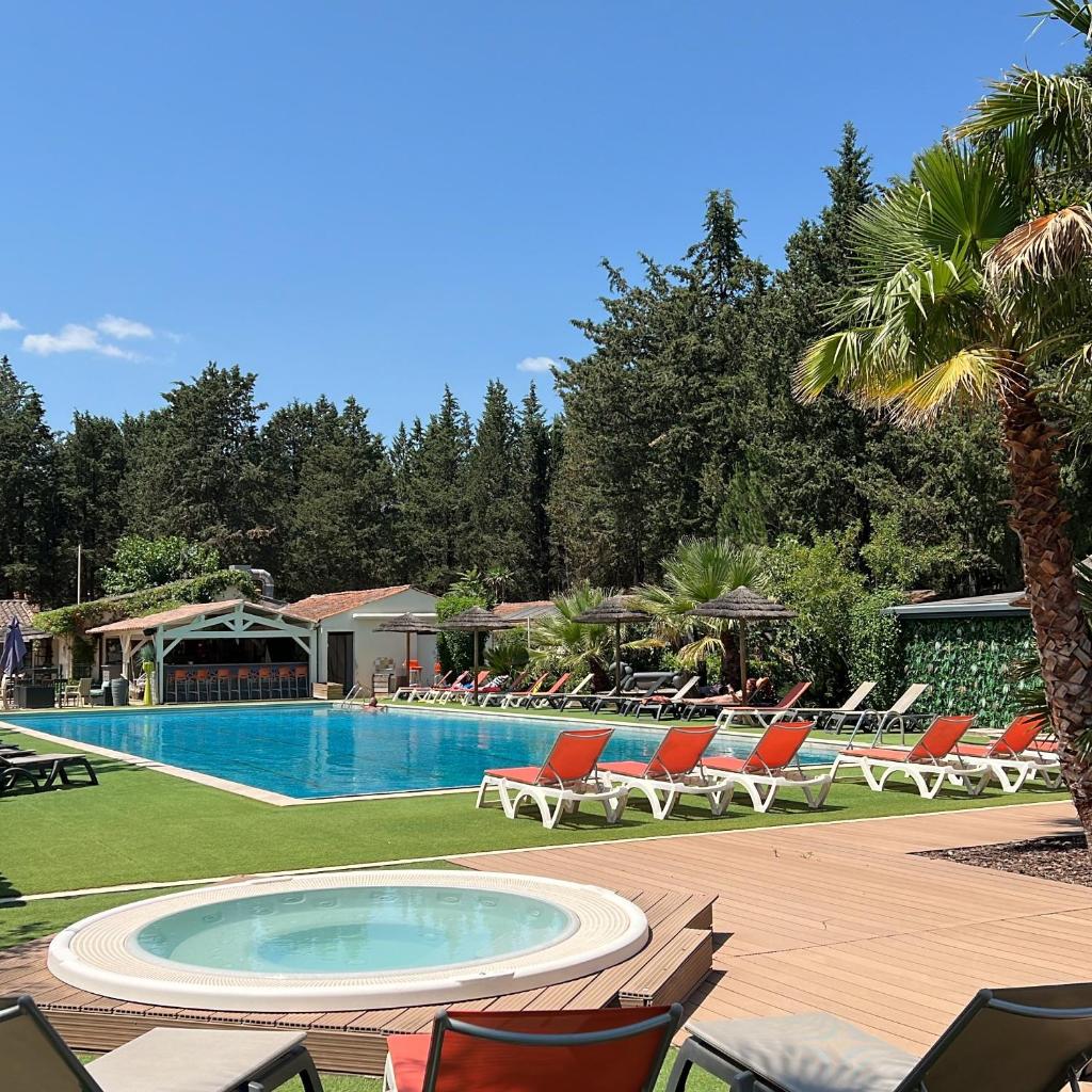 une piscine avec des chaises longues et un complexe hôtelier dans l'établissement La Vallée De Taradeau, à Taradeau