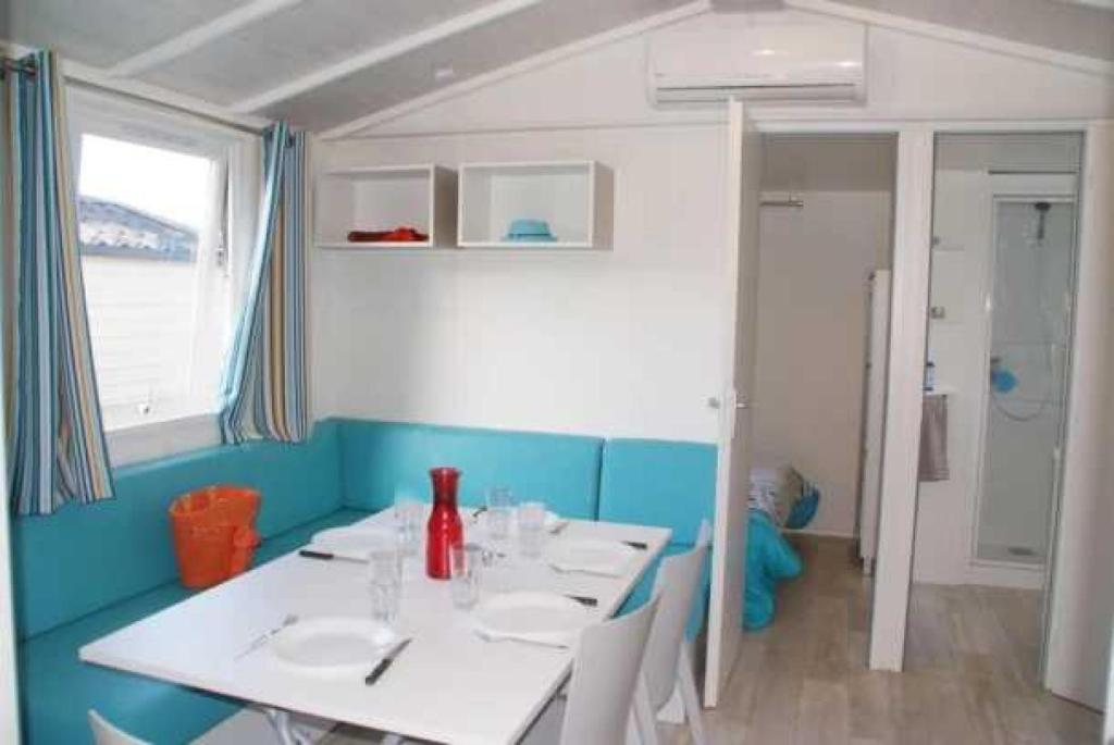 une salle à manger avec deux tables blanches et un mur bleu dans l'établissement Camping 3 étoiles - Parc aquatique - eecegi, à Fréjus