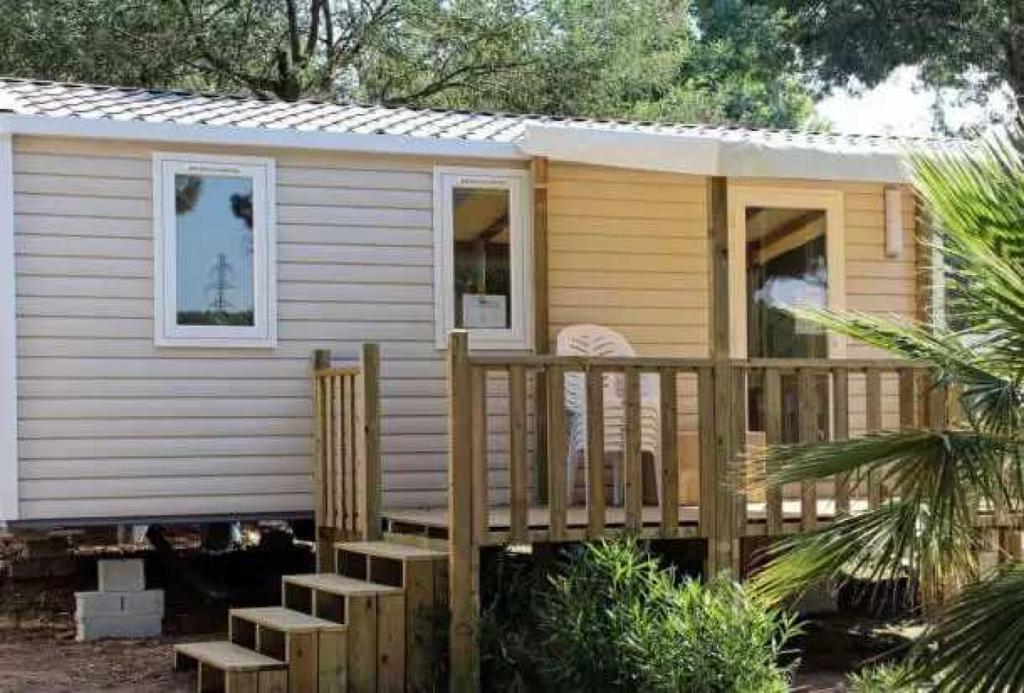 Cette petite maison dispose d'une terrasse couverte en bois et d'escaliers. dans l'établissement Camping 3 étoiles - Parc aquatique - eecegi, à Fréjus