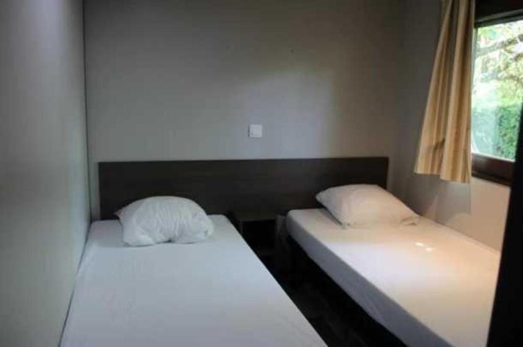 deux lits assis dans une pièce avec une fenêtre dans l'établissement Camping 3 étoiles - Piscine - eehgei, à Castelnau-Picampeau