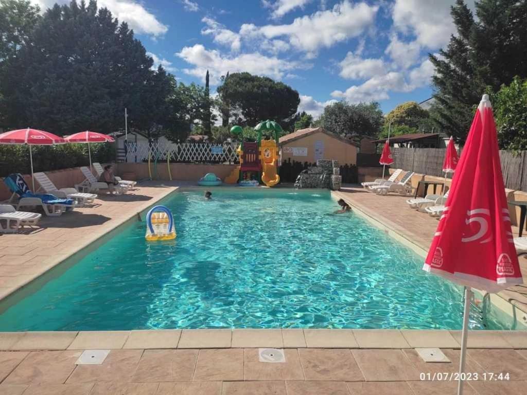 - une piscine avec toboggan et parasols dans l'établissement Camping 3 étoiles - Piscine - eebic0, à Massillargues-Attuech