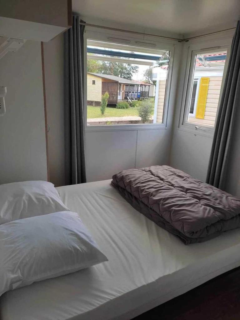 un lit dans une petite pièce avec une fenêtre dans l'établissement Camping 3 étoiles - Piscine - eebic0, à Massillargues-Attuech