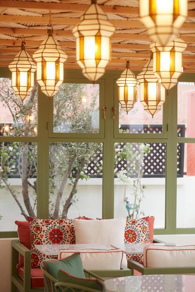 une pièce avec des lustres et des canapés devant les fenêtres dans l'établissement Riad O, à Marrakech