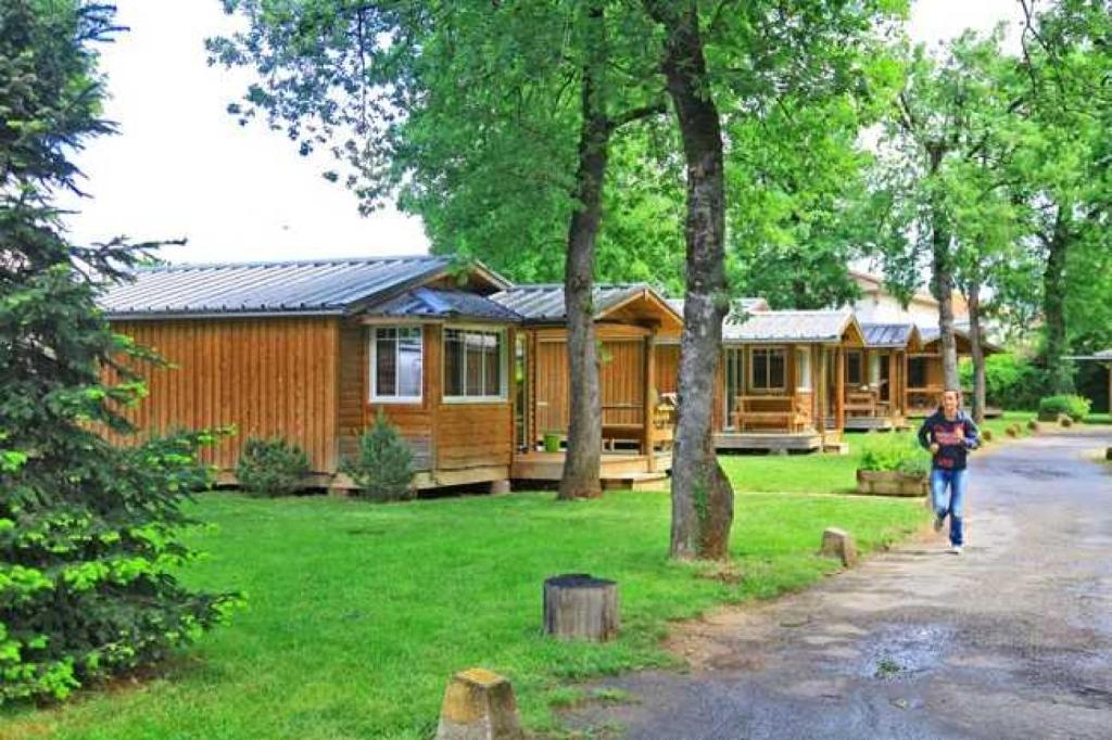 une femme marchant devant une cabane en rondins dans l'établissement Chalet 4 étoiles - Piscine - ef0ccc, à Albi