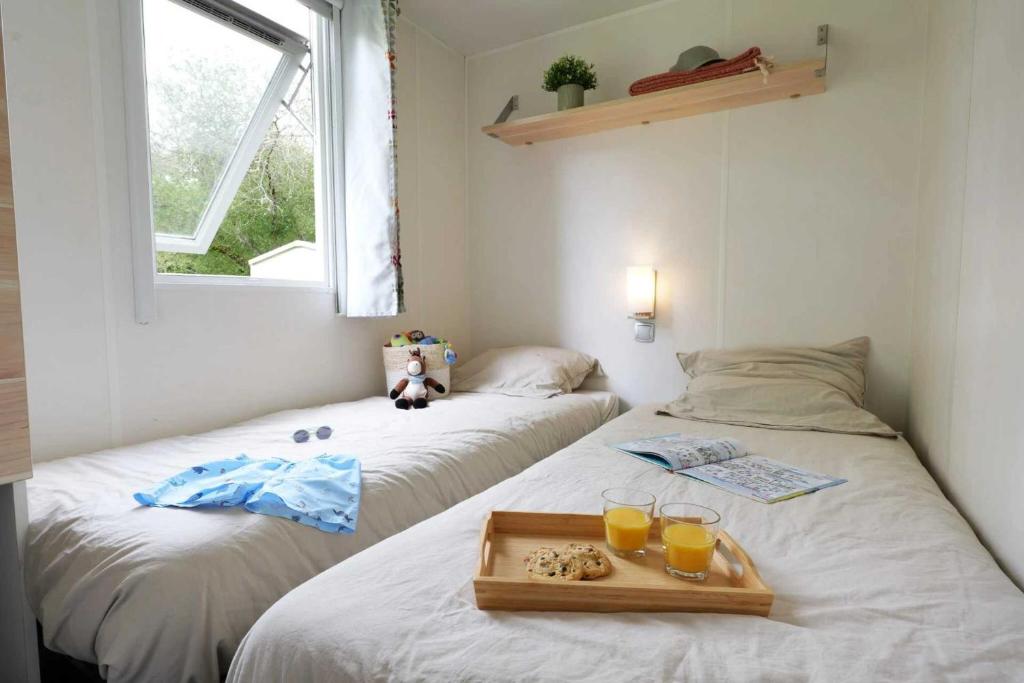 une chambre avec deux lits avec deux verres de jus d'orange dans l'établissement Camping 3 étoiles - Piscine - efc0ab, à Vensac
