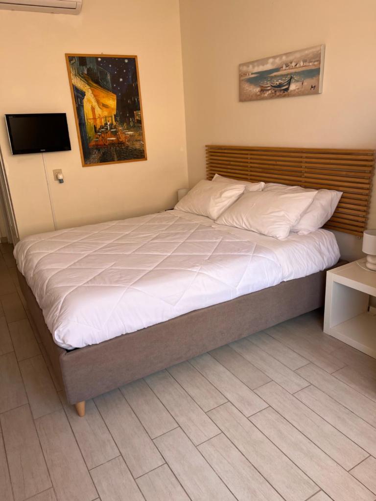 une chambre avec un grand lit avec des draps blancs dans l'établissement Ashur mondello, à Palerme