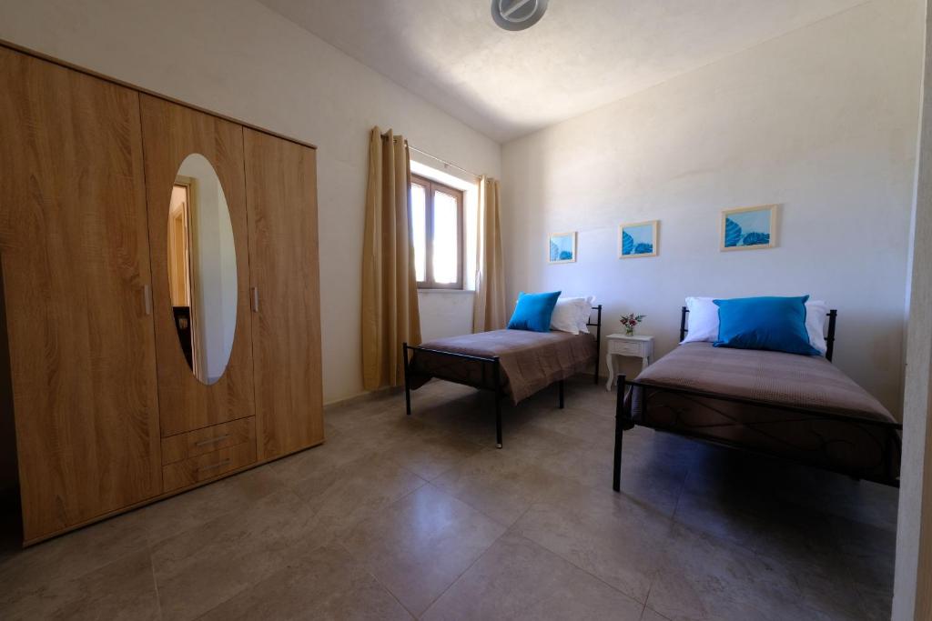 Cette chambre comprend 2 lits et un miroir. dans l'établissement Tenuta con due abitazioni indipendenti, à Martina Franca