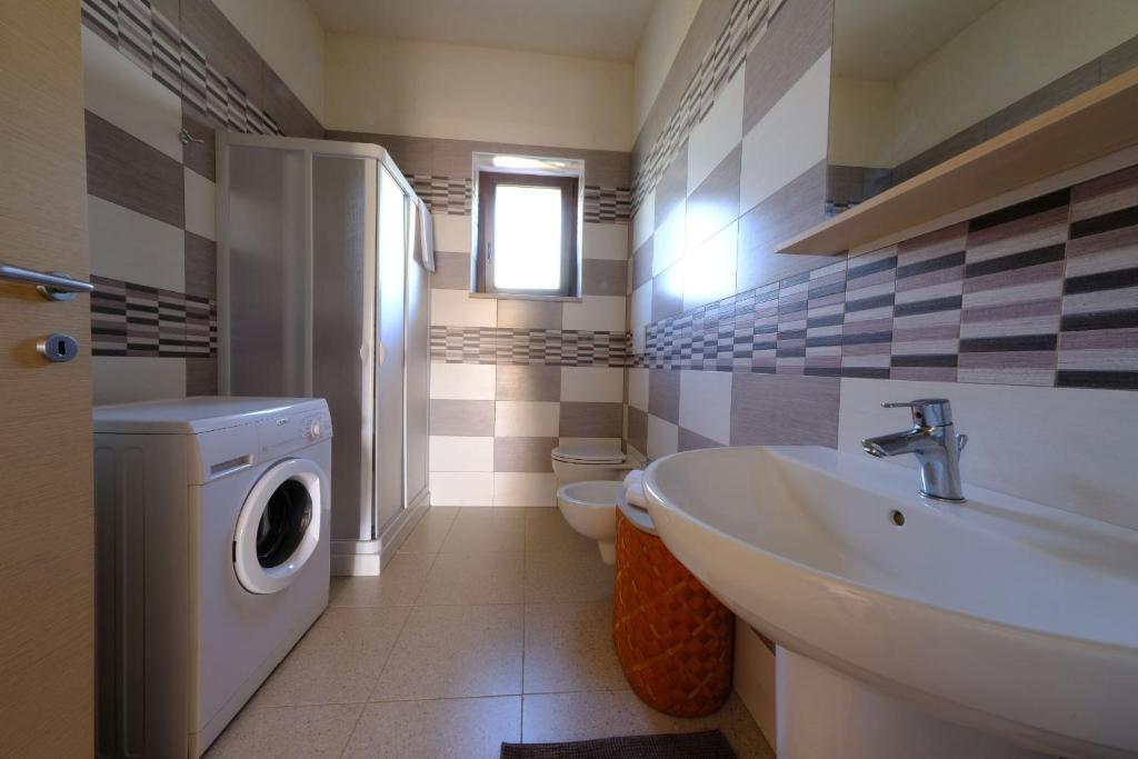 une salle de bain avec une machine à laver et un lavabo dans l'établissement Tenuta con due abitazioni indipendenti, à Martina Franca