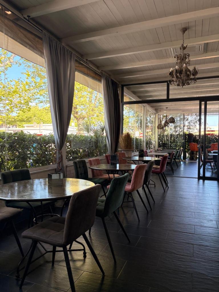 une salle à manger avec tables, chaises et fenêtres dans l'établissement Hotel Atlantic, à Marina di Carrara
