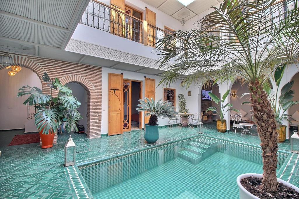 - une piscine bordée de palmiers dans un bâtiment dans l'établissement Riad Darchica, à Marrakech
