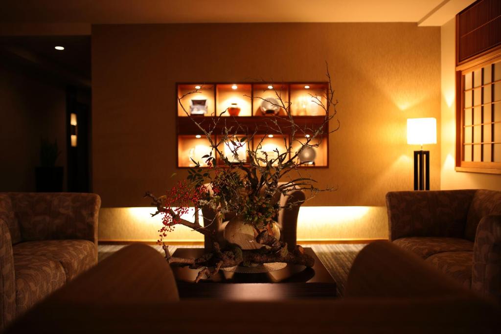 un salon avec un canapé et une table avec des fleurs dans l'établissement Ryotei Matsuya Honkan Suizenji, à Kumamoto