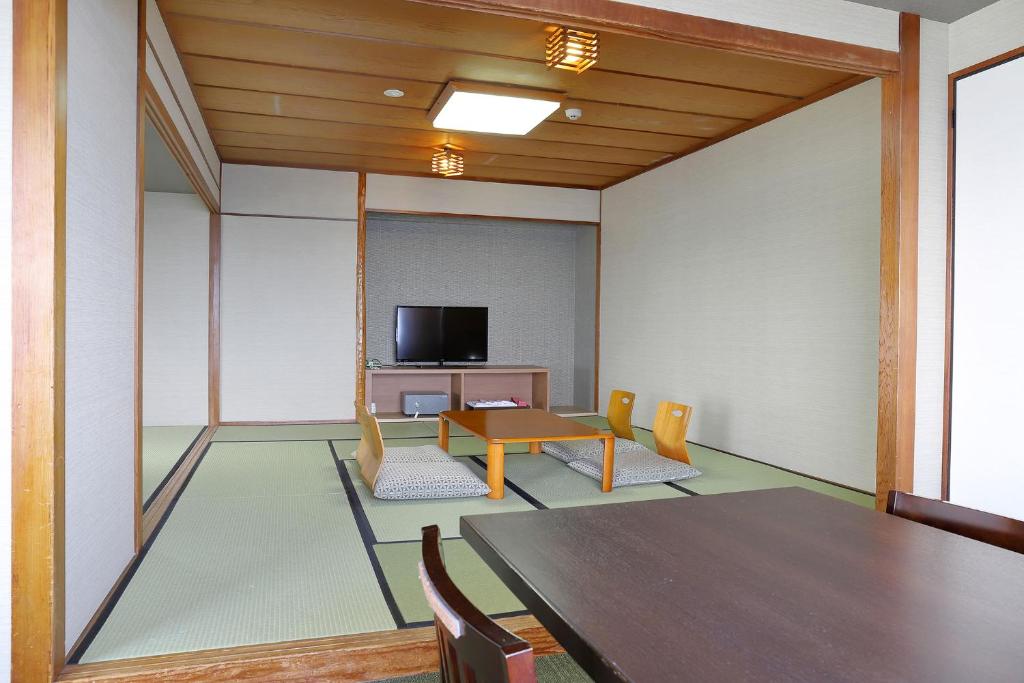 une pièce avec une table, des chaises et une télévision dans l'établissement Ooedo Onsen Monogatari Beppu Seifu, à Beppu