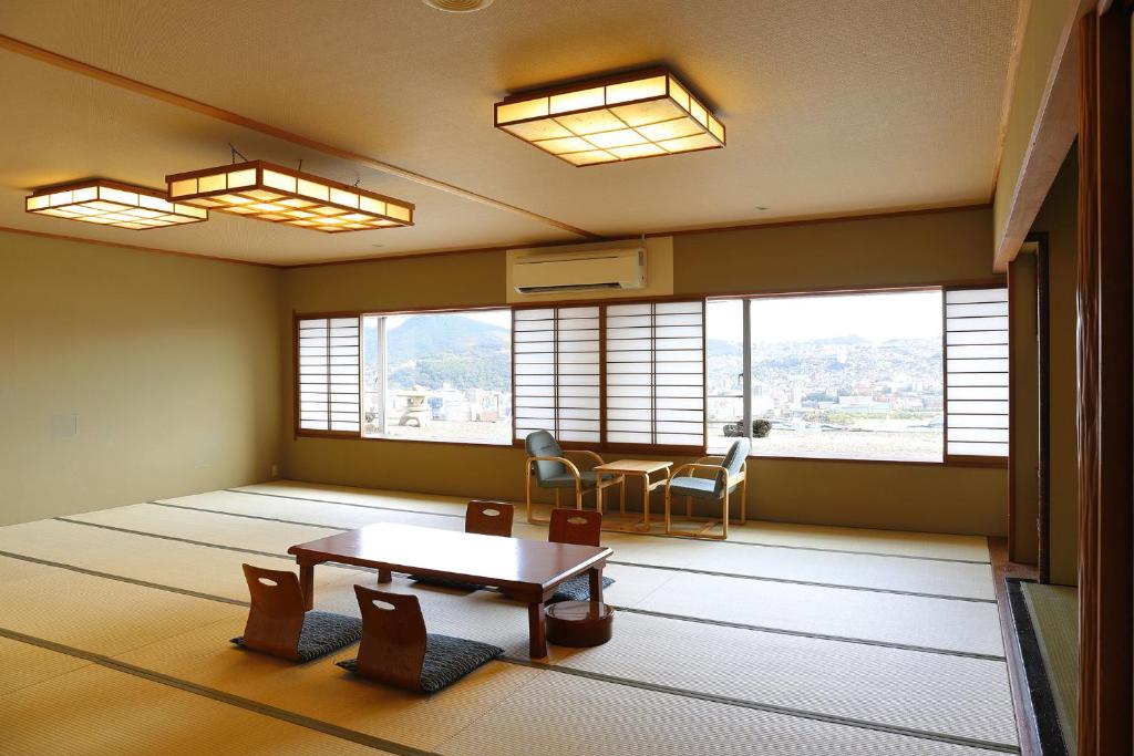 une pièce avec une table, des chaises et des fenêtres dans l'établissement Ooedo Onsen Monogatari Nagasaki Hotel Seifu, à Nagasaki