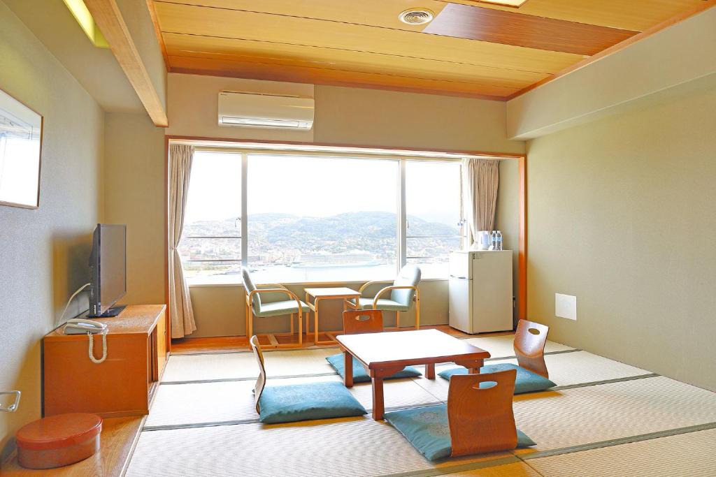 une pièce avec une table et des chaises et une grande fenêtre dans l'établissement Ooedo Onsen Monogatari Nagasaki Hotel Seifu, à Nagasaki