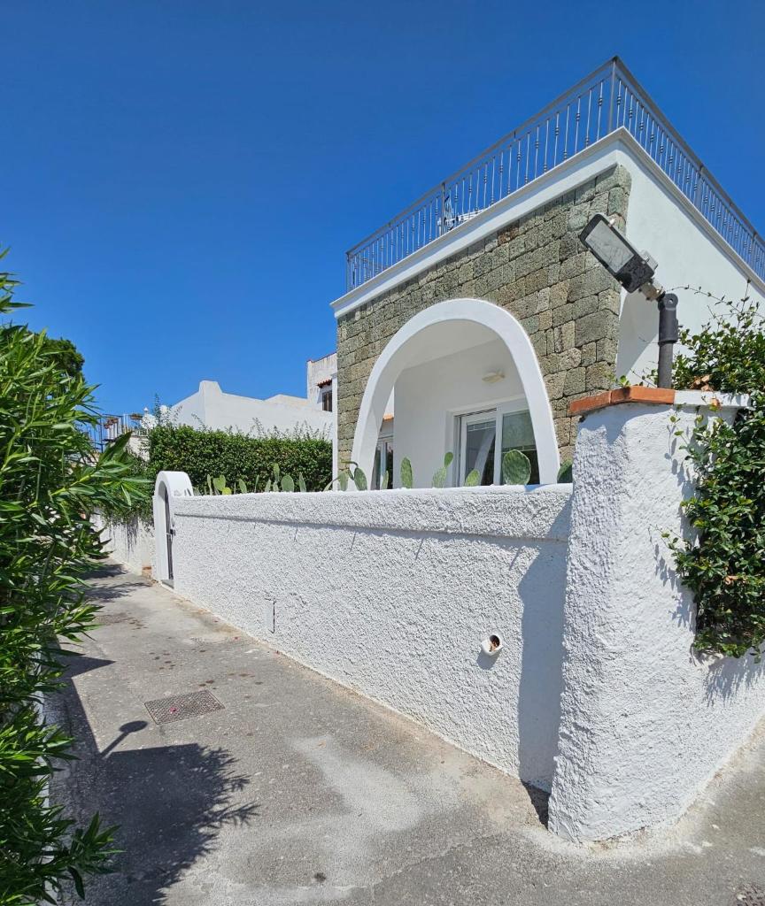 une maison blanche avec un mur en pierre à côté d'une rue dans l'établissement Villa Dafne, à Ischia