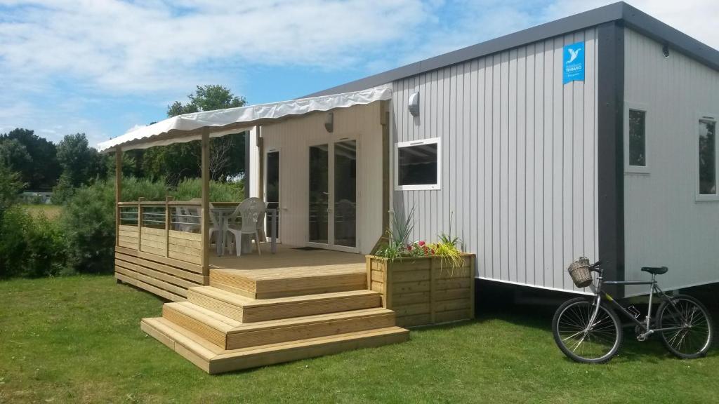 une maison avec une terrasse et un vélo sur l'herbe dans l'établissement Bontempo Village La Yole, à Saint-Jean-de-Monts