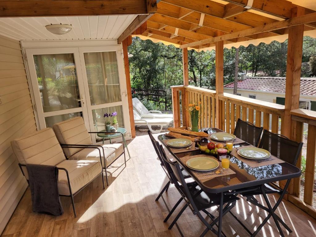 - une terrasse couverte avec une table et des chaises dans l'établissement Mobilehome Leï Suves Côte d'Azur, à Roquebrune-sur Argens