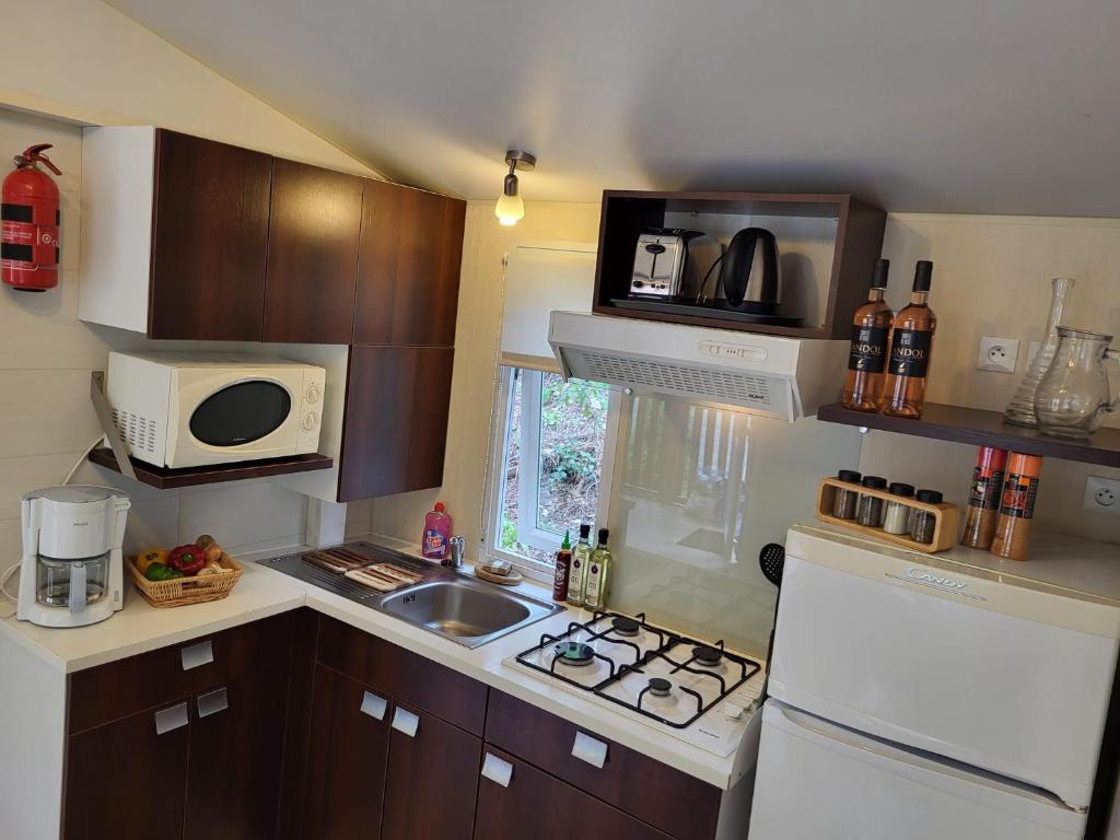 une petite cuisine avec un évier et un micro-ondes dans l'établissement Mobilehome Leï Suves Côte d'Azur, à Roquebrune-sur Argens