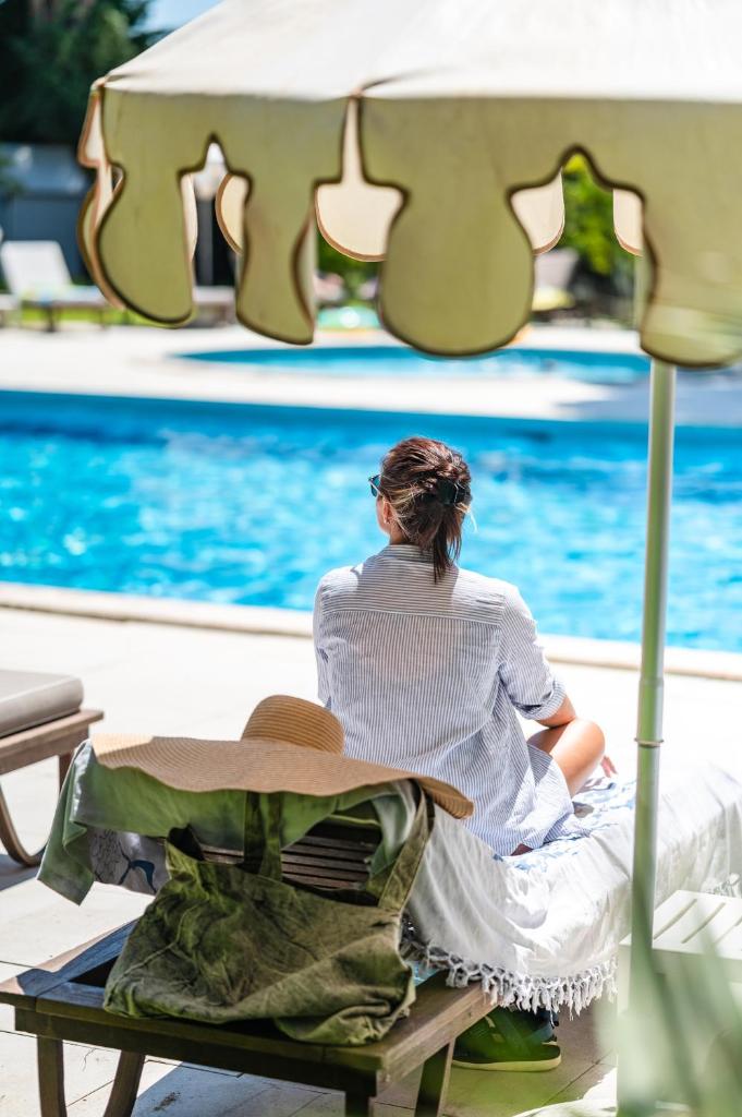 une femme assise sur une chaise à côté d'une piscine dans l'établissement Park Hotel Maracaibo, à Lido di Jesolo