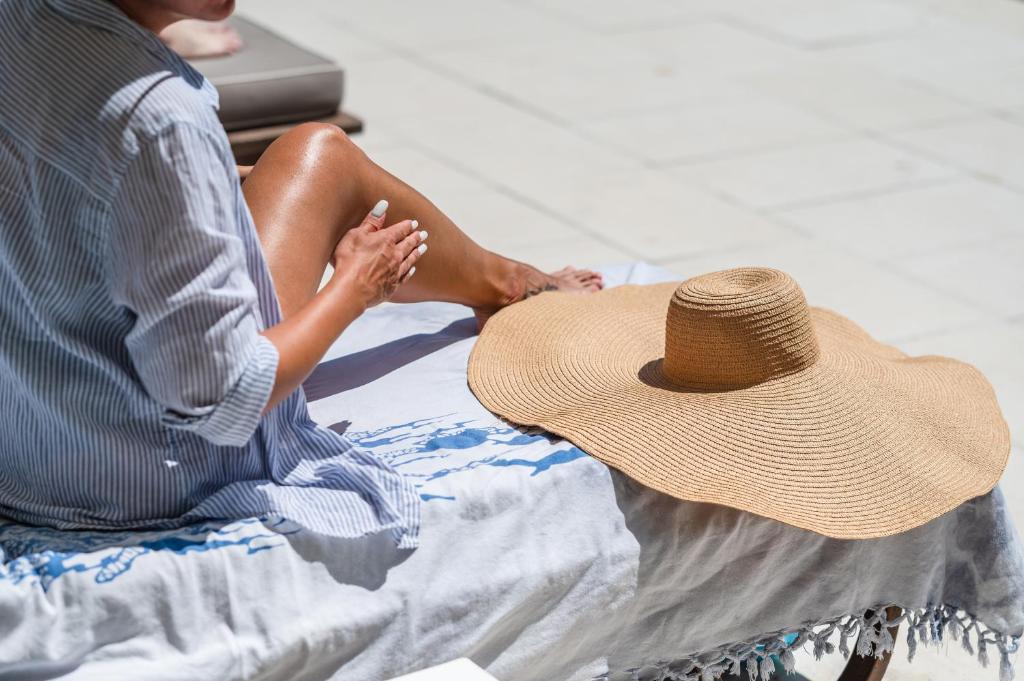 une femme assise sur un lit avec un chapeau de paille dans l'établissement Park Hotel Maracaibo, à Lido di Jesolo