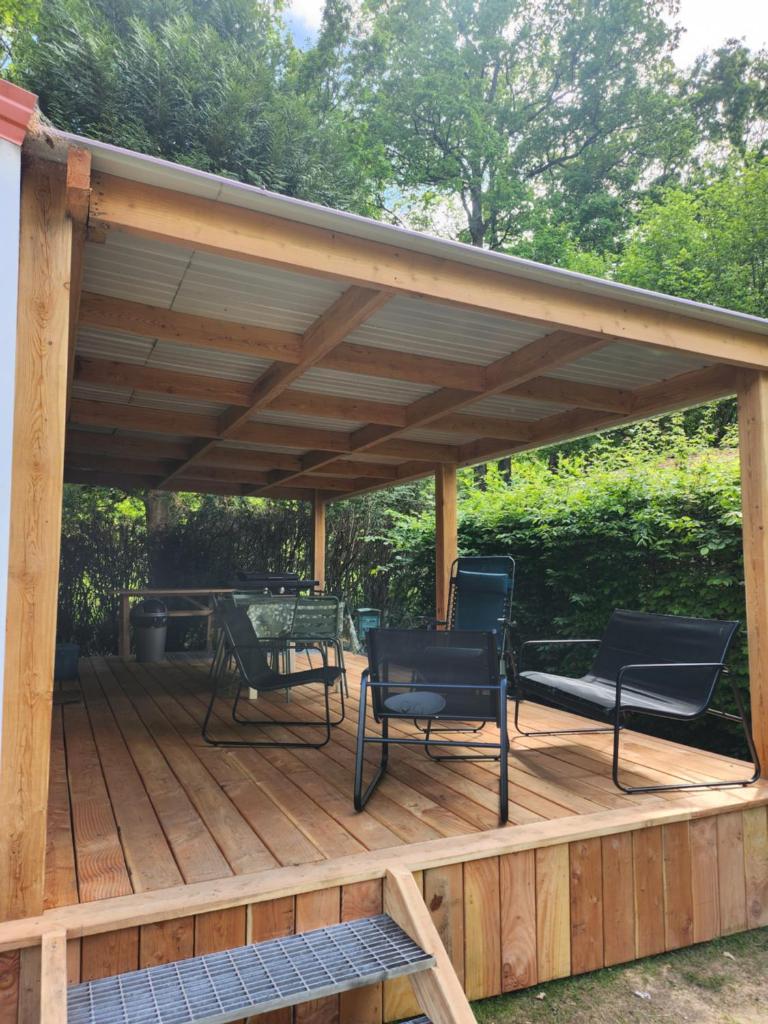 une pergola en bois avec des chaises et une table sur une terrasse dans l'établissement Mobilhome les pieds dans l eau avec piscine, à Saint-Gérons 5 autres photos