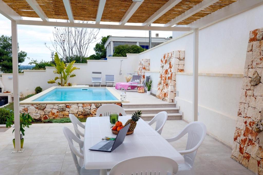 un patio avec une table et des chaises et une piscine dans l'établissement Villa Solimar -Sole del Salento, à Torre Vado