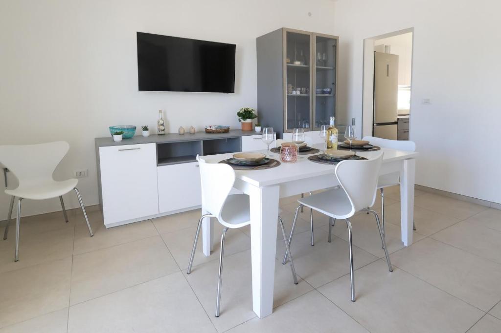 une salle à manger blanche avec une table et des chaises blanches dans l'établissement Villa Solimar -Sole del Salento, à Torre Vado