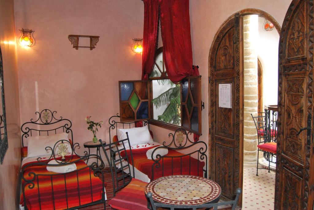 une chambre avec deux lits, une table et des chaises dans l'établissement Caverne d'Ali Baba, à Essaouira