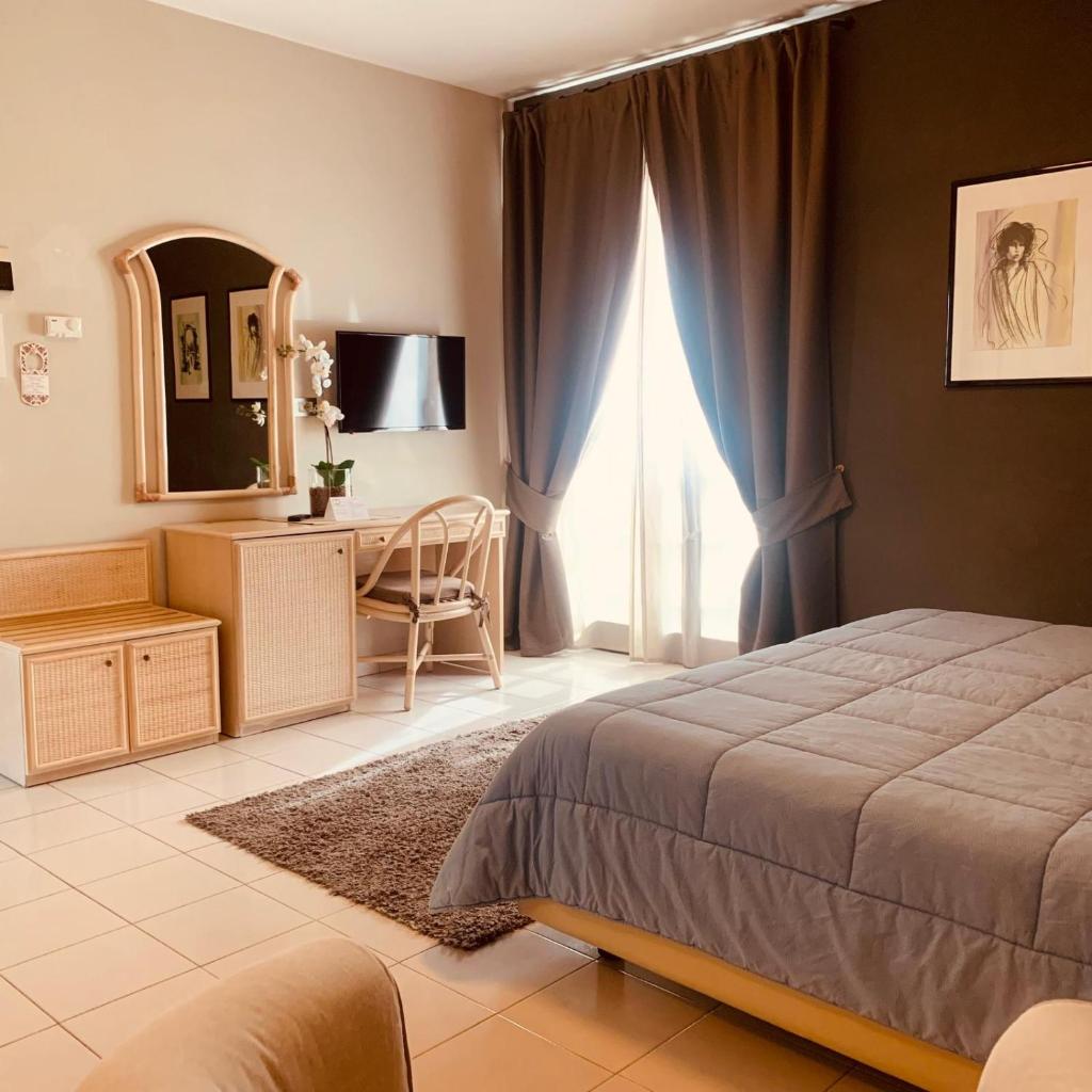 une chambre avec un lit, un bureau et un miroir dans l'établissement River Park Hotel, à Ameglia 95 autres photos
