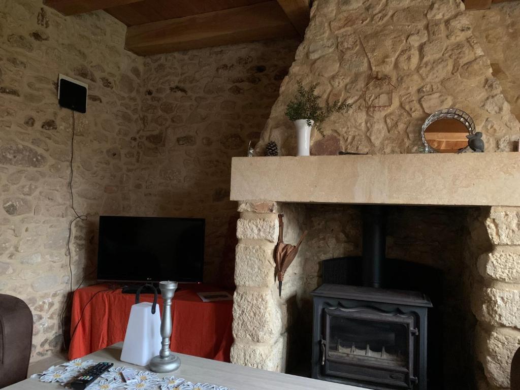 un salon avec une cheminée en pierre et une télévision dans l'établissement Gîte à la Ruelle "Pierre et Mamie" !, à Savignac-de-Miremont