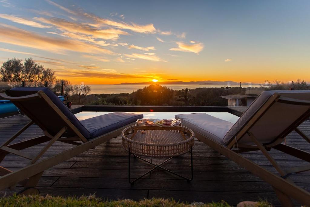 une terrasse avec deux chaises et une table et le coucher du soleil dans l'établissement Villa Gaia, à Quartu Sant'Elena