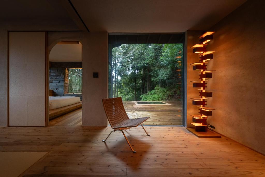 une chambre avec une chaise devant une porte coulissante en verre dans l'établissement 奥武雄温泉　風の森, à Ureshino