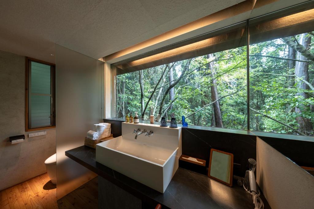 une salle de bain avec un lavabo et une grande fenêtre dans l'établissement 奥武雄温泉　風の森, à Ureshino