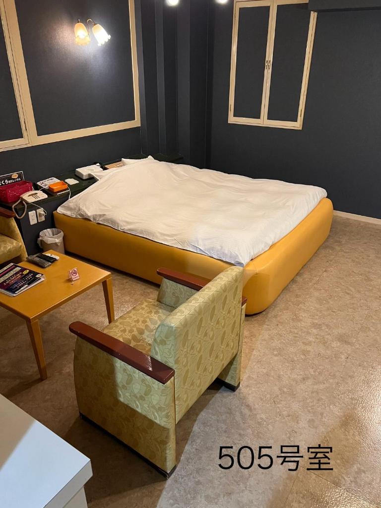 Cette chambre comprend un grand lit et une chaise. dans l'établissement ホテルQ adult only, à Kashiwazaki
