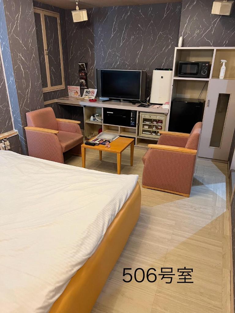 Cette chambre comprend un lit, une télévision et des chaises. dans l'établissement ホテルQ adult only, à Kashiwazaki