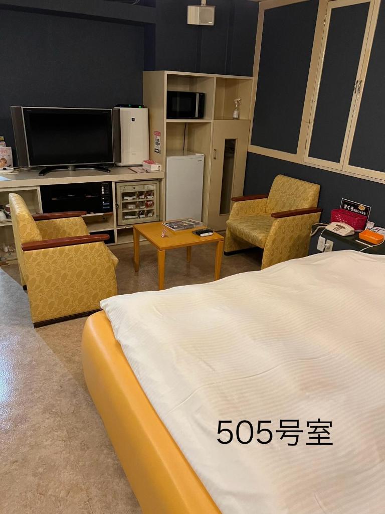 - une chambre avec un lit, une télévision et des chaises dans l'établissement ホテルQ adult only, à Kashiwazaki