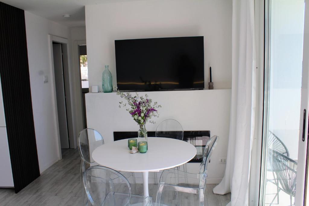 une salle à manger blanche avec une table et des chaises blanches dans l'établissement Conca Verde c21- BEACH FRONT little villas POOL, private JACUZZI sea view, à Marina dʼAndora