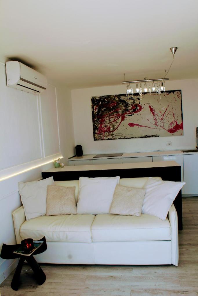 un canapé blanc dans un salon avec un tableau dans l'établissement Conca Verde c21- BEACH FRONT little villas POOL, private JACUZZI sea view, à Marina dʼAndora 39 autres photos