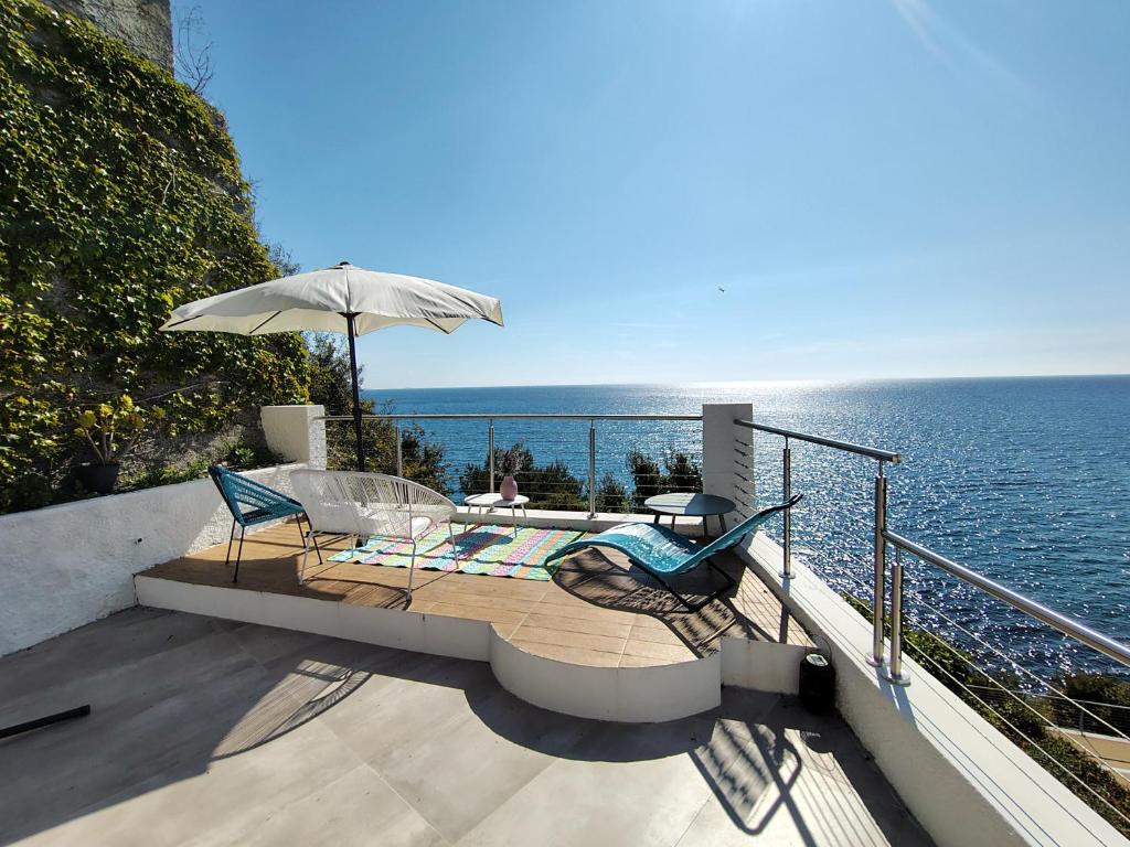 une terrasse avec une table et un parasol et l'océan dans l'établissement Conca Verde c21- BEACH FRONT little villas POOL, private JACUZZI sea view, à Marina dʼAndora