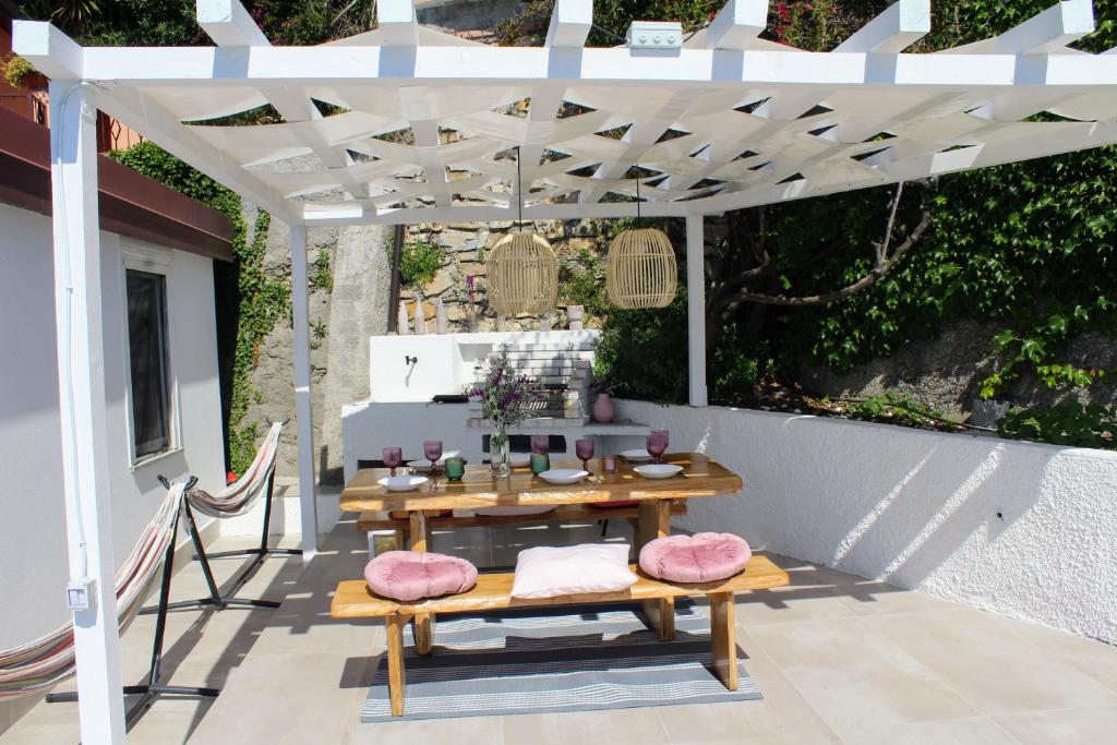une table en bois et des bancs sous une pergola blanche dans l'établissement Conca Verde c21- BEACH FRONT little villas POOL, private JACUZZI sea view, à Marina dʼAndora